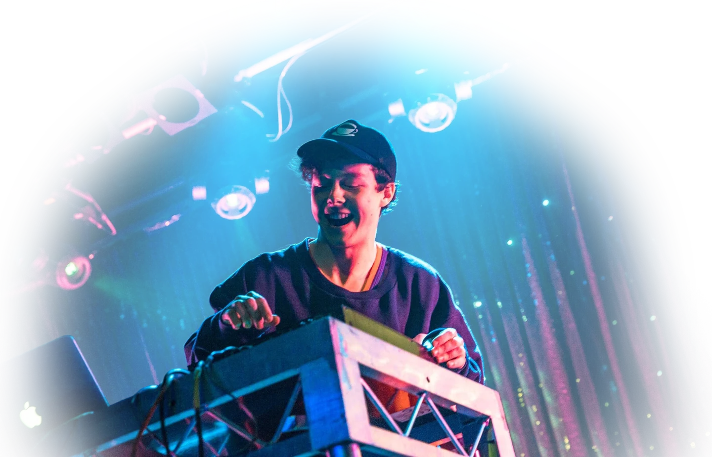 Jonny Woolley operating a sound desk under cyan and magenta stage lighting